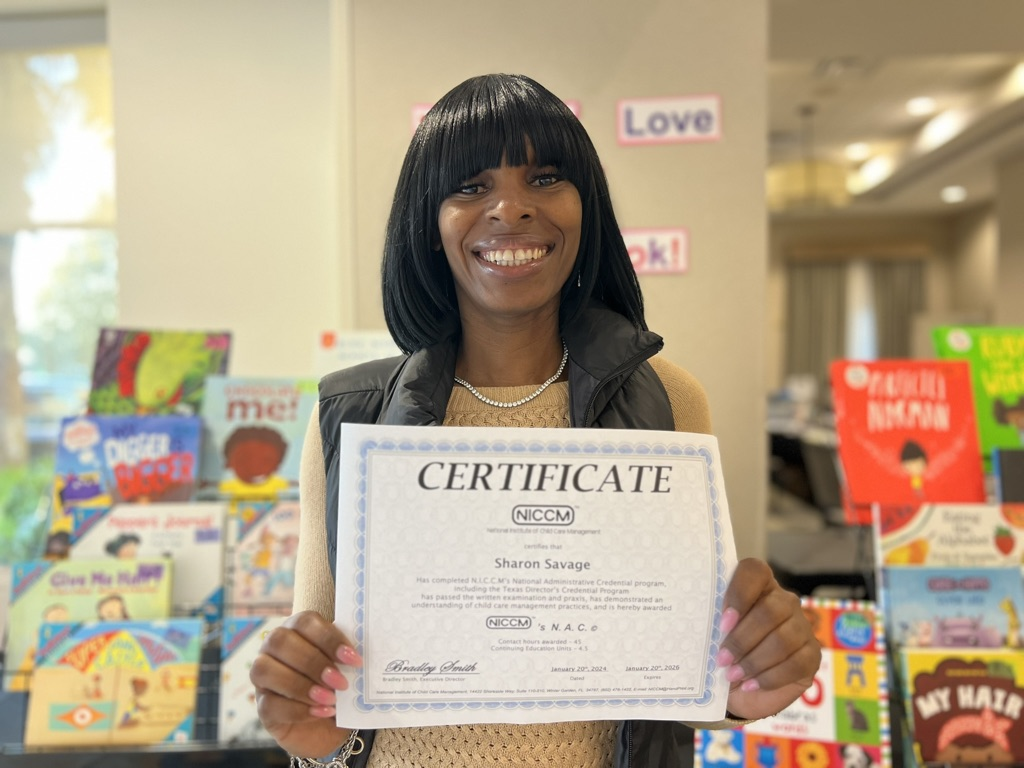 Woman holding NAC certificate in a preschool classroom